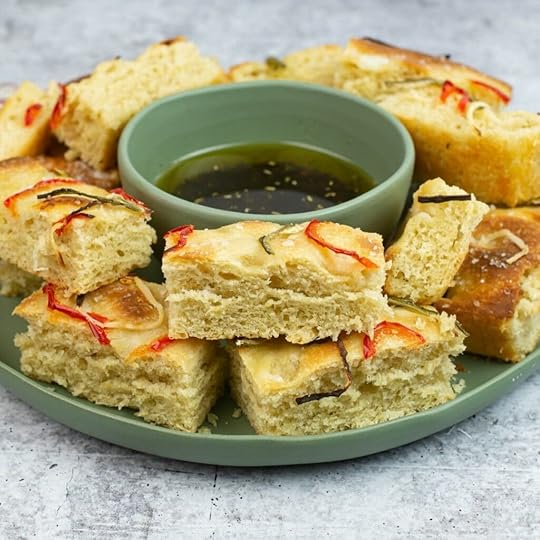 Sourdough Focaccia cut into pieces on a plate with a bowl of dipping oil.