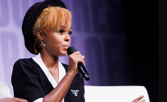 Medium shot of Janelle Monae, speaking into a microphone on stage