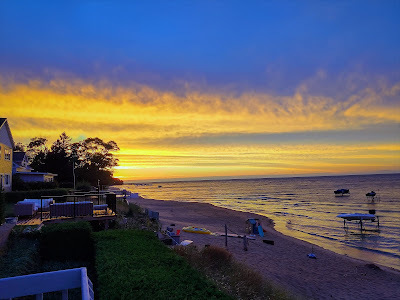 Looking west along the beach to the golden sunset. Decks and water toys are visible.