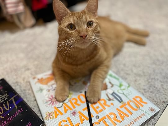 My cute cat Glyph, an adorable orange tabby, lying across the book Aaron Slater Illustrator