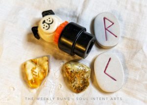 Elder Futhark runes Raidho and Kenaz carved into porcelain tiles, with Fehu and Ansuz carved into polished Baltic amber, with the elementPlastic represented as the Little People Dog, with the The Weekly Rune - Soul Intent Arts at the bottom