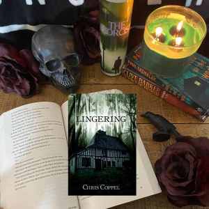 Lingering book surrounded by a black skull, green candle, red roses, and a black crow figurine