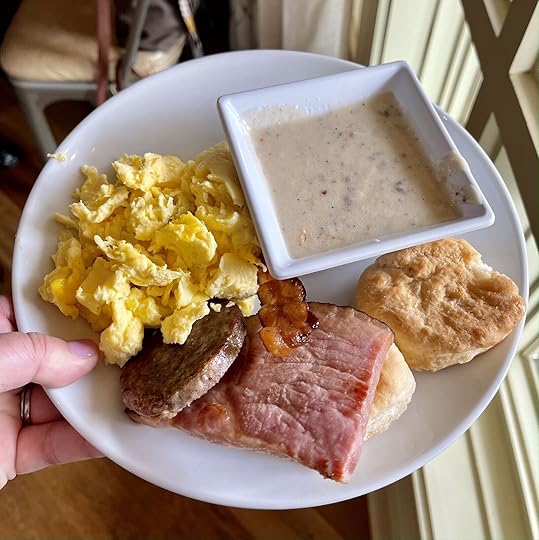 woman holding a white plate with sausag and biscuit - dollywood food