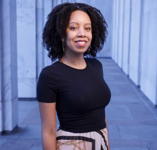 Three-quarters portrait of Ashley Jones, posed in covered entrance of the Madison Building. She's smiling and wearing a black pullover top.