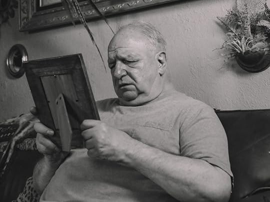 older man looking at photograph grieving, thankful