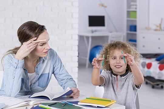 A distracted child plays with pencils while sitting at a table with his mother, who is trying to help him do homework. Getting the right diagnosis with ADHD and dyslexia is very important.