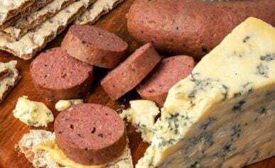 Slices of braunschweiger sausage with crackers, mustard and blue cheese.