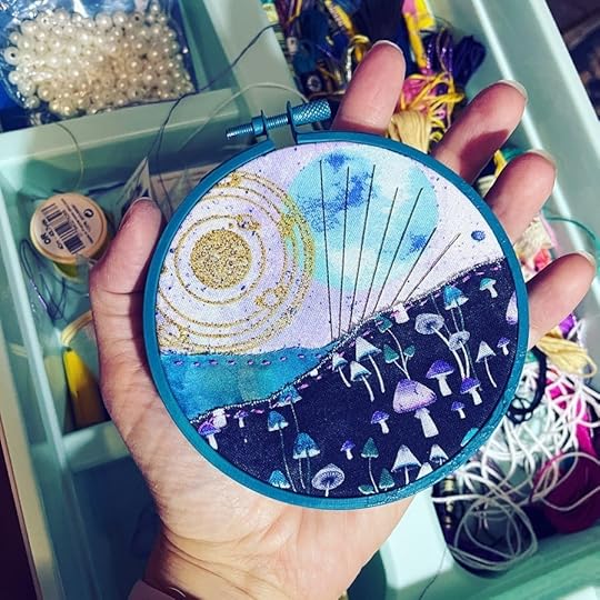 turquoise painted embroidery hoop with a mountain scene under a celestial sky