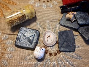 Elder Futhark runes Gebo, Mannaz, and Dagaz with a beige ceramic owl, a vial of lemon zest, a key and other items on beige and teal patterned background
