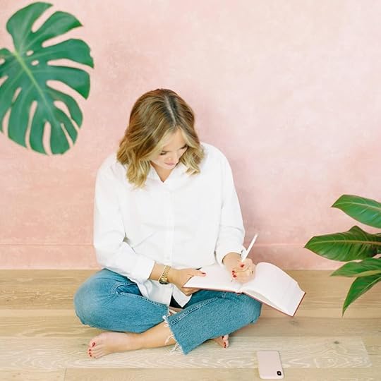 Woman wearing white blouse and blue jeans and writing in journal