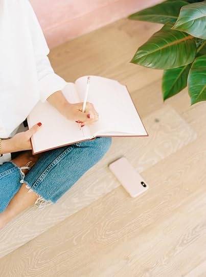 How to win NaNoWriMo, a woman sitting cross-legged on floor and writing in her journal