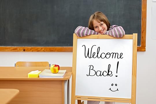 An older elementary school student stands in a classroom behind a small whiteboard easel that says welcome back. Many kids are playing catch-up with education and covid-19.