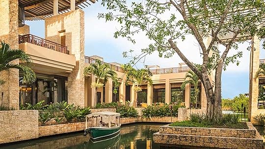 lobby and banyan tree at the banyan tree mayakoba with a boat drifting through one of the canals in the lobby