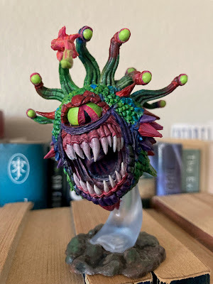 a DnD beholder monster miniature, painted in obnoxiously bright lime green and hot pink