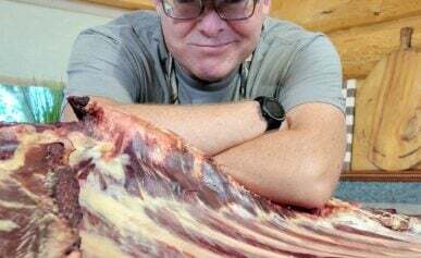 Hank Shaw smiling over a rack of bison ribs.