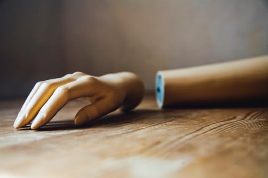 Image: a mannequin's arm, with the hand separated from it, rests on a table.
