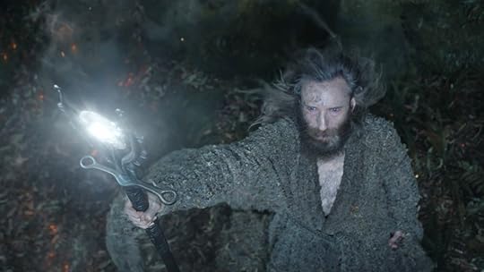 The Stranger holds up a glowing staff to use magic on The Rings of Power