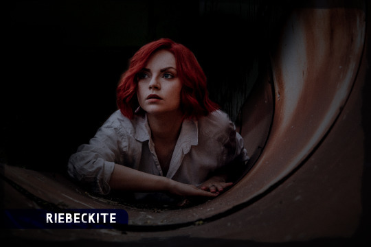 Red-haired woman crawling through dark duct pipe