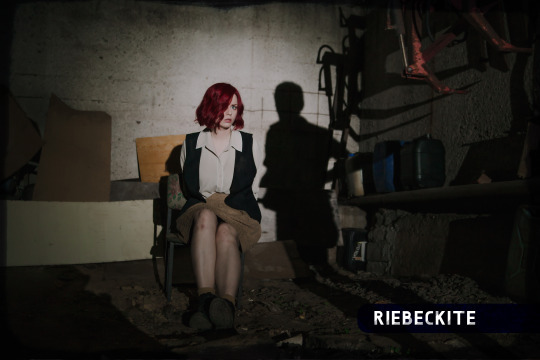 Red-haired woman restrained in a chair in a dark room