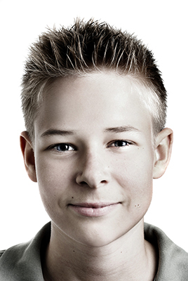 A photo where a boy looks directly at the viewer, smiling and looking positive.