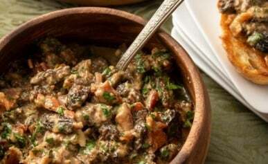 Creamy mushrooms in a bowl with toast alongside.