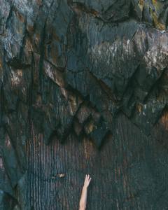 Holding On - a hand is shown reaching up in front of a rock or cave wall