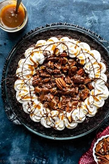 caramel turtle pecan brownie pie on Oreo cookie crust with piped whipped cream around the edges on blue backdrop.