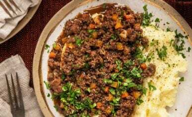 A plate of Scottish mince and tatties with a glass of beer.