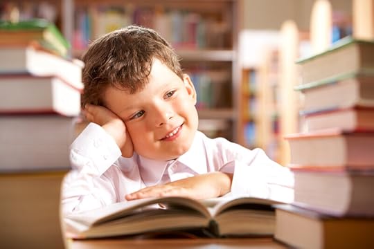 A boy reading at a table in a library surrounded by stacks of books. He has found a book that speaks to him, possibly because he has dyslexia and the book contains a hero of self-reference he can relate to.