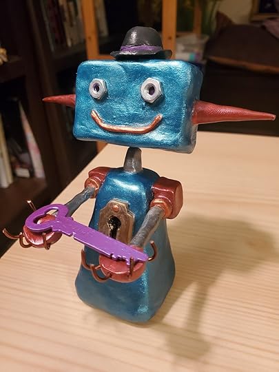 Blue, silver, bronze, and burgundy robot sculpture made of polymer clay. The robot is smiling and holding out an antique key painted purple. The robot has a keyhole attached to its chest. Sculpture is by Andy Reynolds.