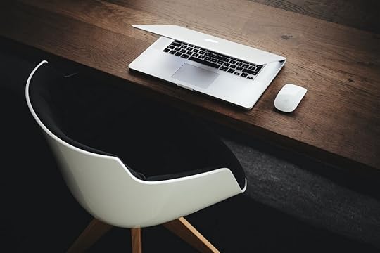 A photo of a white and black chair, brown desk, and grey/black laptop. Photo by Luca Bravo via Unsplash