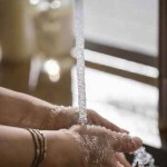 Person washing hands in bathroom sink