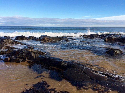 waves crash at St Combs beach. Shadows and light.