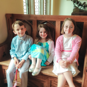 young William, Marilee, and Penny sit on a bench inside at Taft