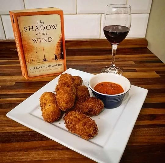 Crispy Spanish croquettes with a glass of wine and a copy of The Shadow of the Wind