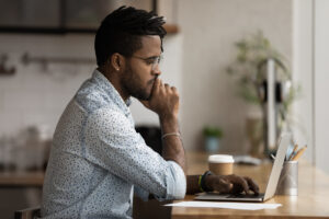 Person looking at a laptop and thinking
