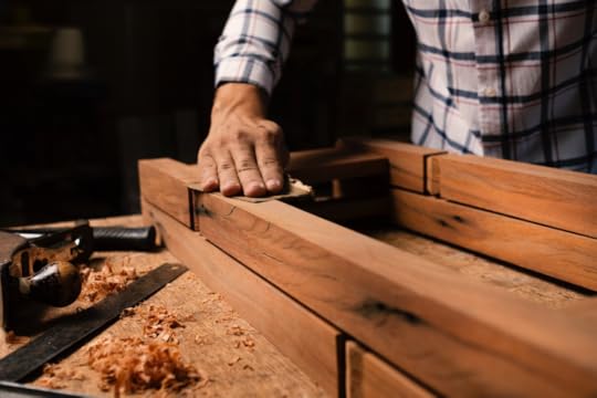 Image: a woodworker sands a project in his shop.