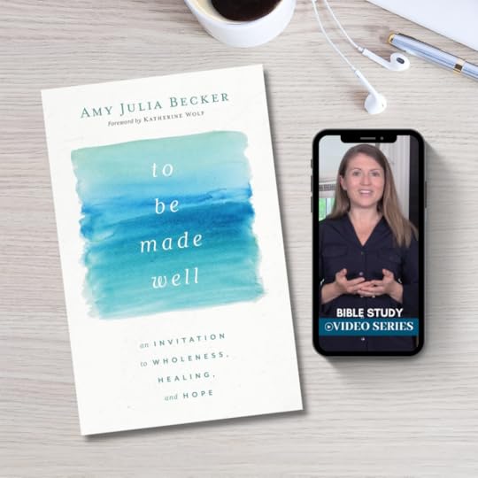 desk with coffee mug, notebook and pen, the book To Be Made Well, and a phone with Amy Julia video teaching on screen.