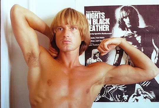 Peter Berlin poses topless next to a poster for his film