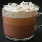 clear glass mug of crockpot hot chocolate on black table.