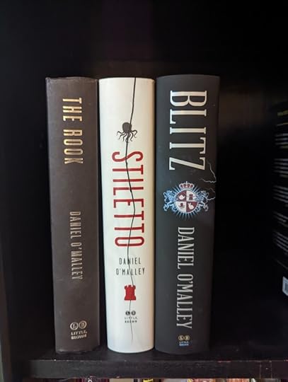The Rook trilogy of books (also called The Checquy Files) by Daniel O'Malley sitting on a shelf.