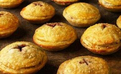 A dozen venison mincemeat pies on a cutting board.