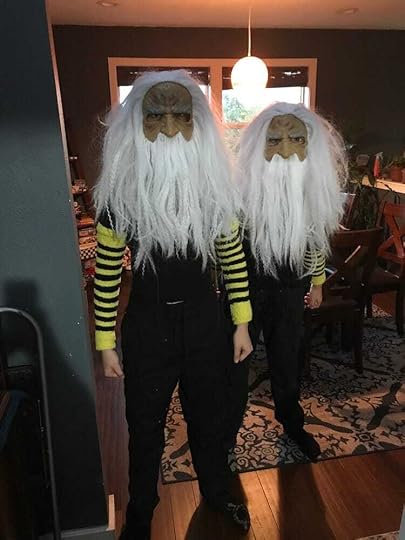 two people dressed in black with yellow-and-black arm-warmers and identical old-man-with-white-hair masks