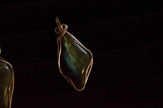 A wire-wrapped black opal gemstone against a black background