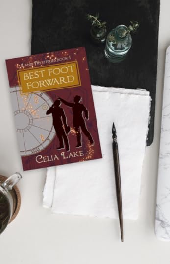 Copy of Best Foot Forward lying on a desk with a dip pen, bottle of ink, and paper. The cover has a deep red background with map markings in a dull purple. Two men in silhouette stand, looking up at a point in the top left. An astrology chart with different symbols picked out takes up the left side of the image, with glowing stars curving up to the title.