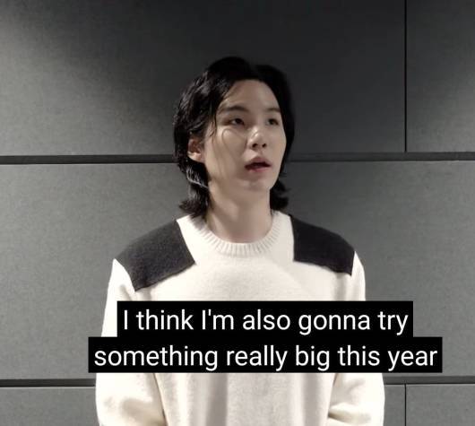 Image of Min Yoongi aka SUGA of BTS dressed in white in front of a grey wall. Text/caption reads 