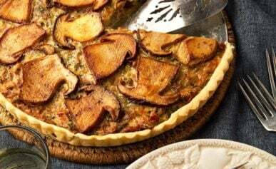 A mushroom tart with a wedge cut out of it, ready to eat.