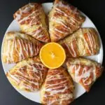 wedges of orange scone on a round platter around a half cut orange.