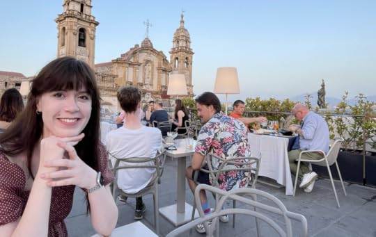 Monica Varner at an outdoor restaurant with a cathedral and blue skies in the background.