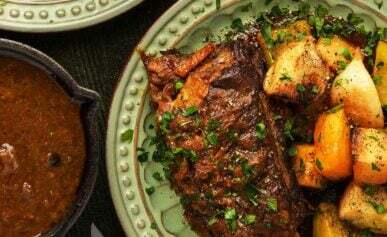 Beer braised bison short ribs on a plate with root vegetables.